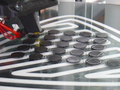3D Drucker trägt Filament auf Heizplatte auf, sodass zwölf schwarze Einkaufchips entstehen